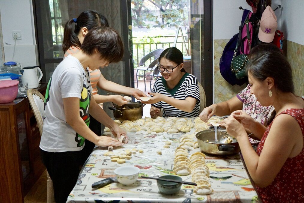 Group of people cooking dumplings together at a table